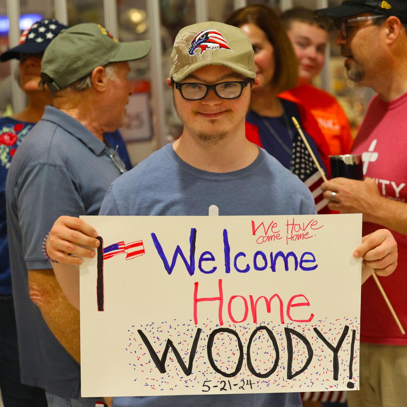 Welcome Home Woody sign is held up at Honor Flight Return Home.JPG
